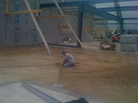 After heights were all figured out, we worked on creating a solid base for the interlock, protecting it from shifting. We allow for small lifts of gravel that get compacted with a plate tamper to reach our 98% compaction which gives you your base. From there we do a final bedding layer which allows us to lay the bricks on a smoother surface. Here he is setting the bars to allow for a consistent slope along the interlock, and also the bedding layer is being pulled by a board (also known as screeding) along the two adjacent pipes.